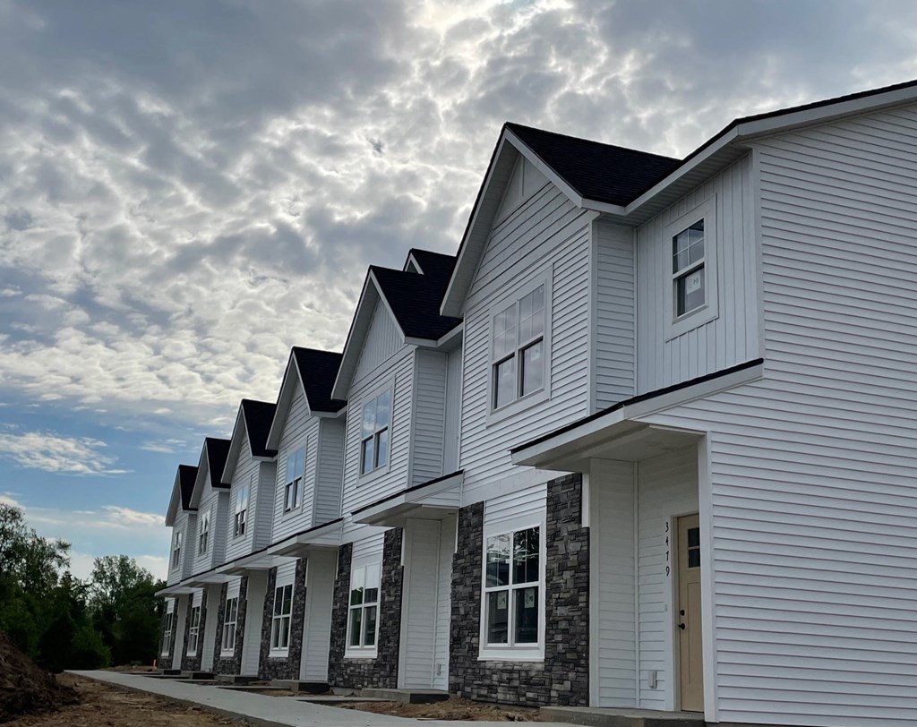 a row of white houses with a cloudy sky in the background