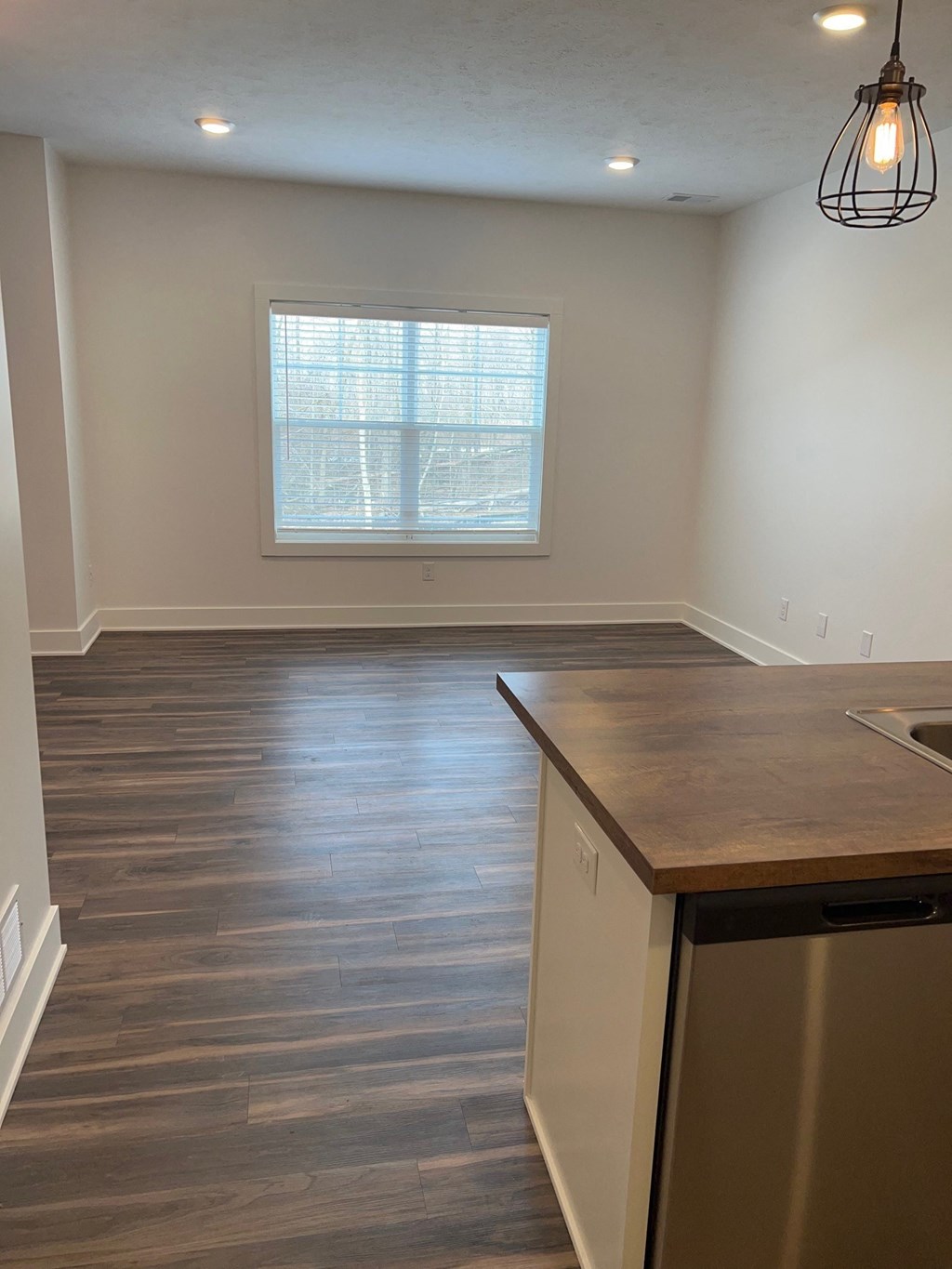 an empty kitchen with wooden floors and a window