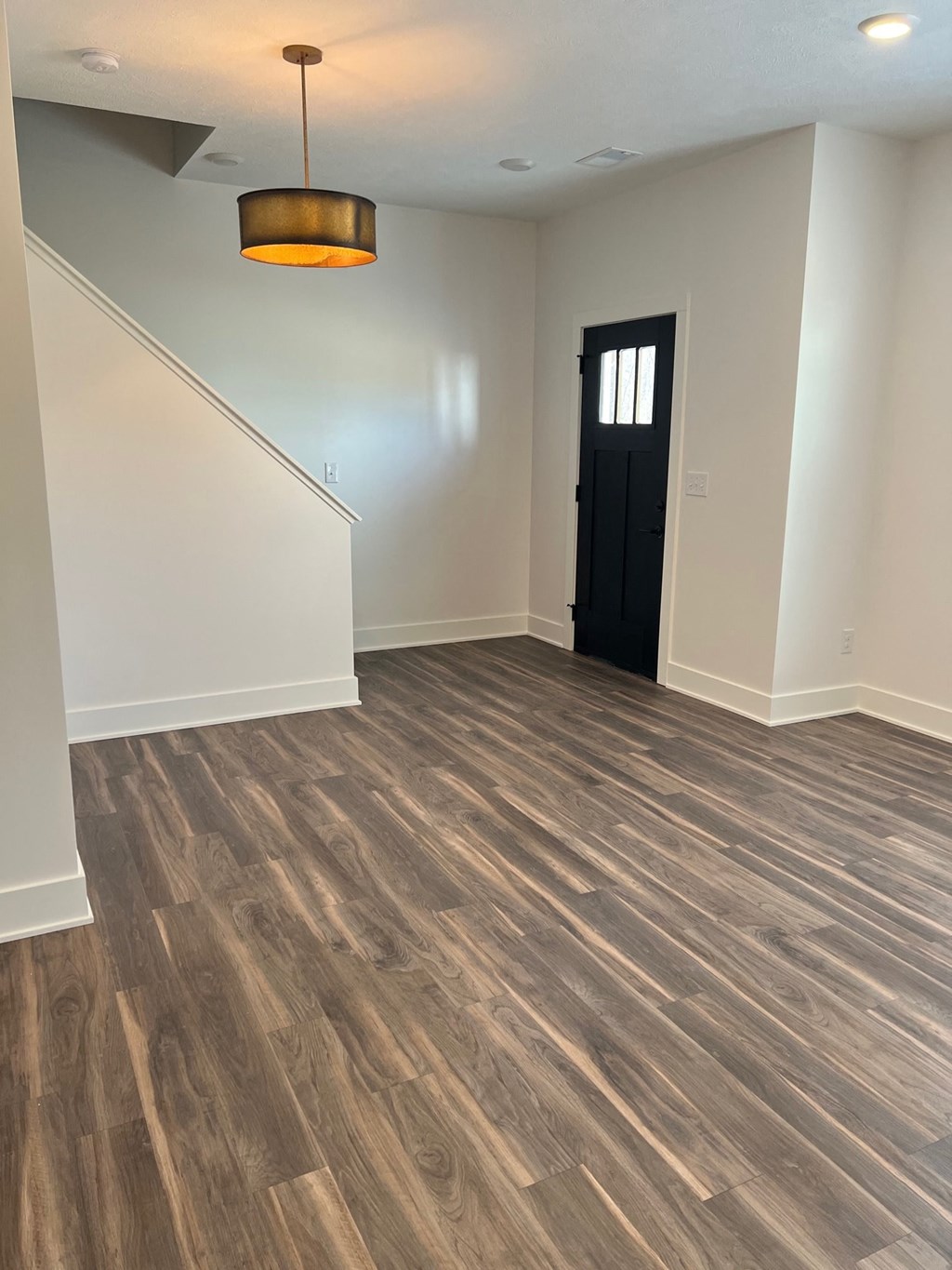 a renovated living room with wood flooring and a black door