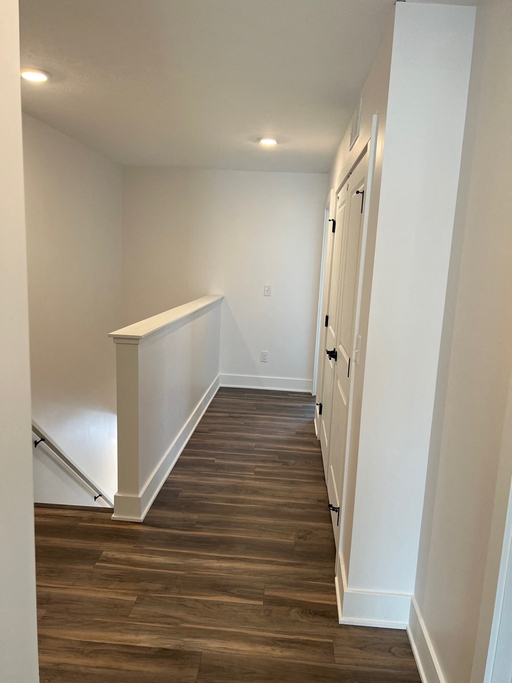 a look down the hallway of a new home with wood floors and white walls