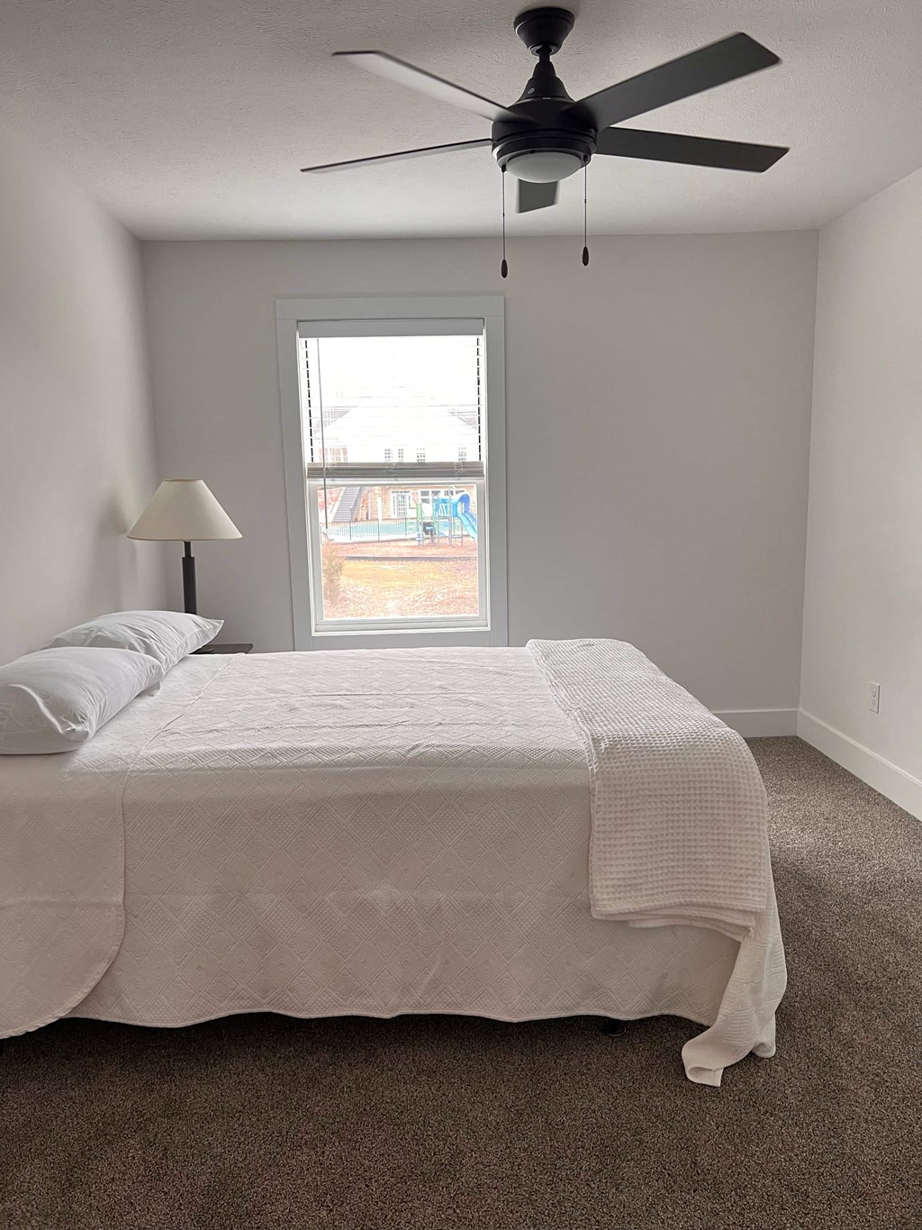 a bedroom with a white bed and a ceiling fan