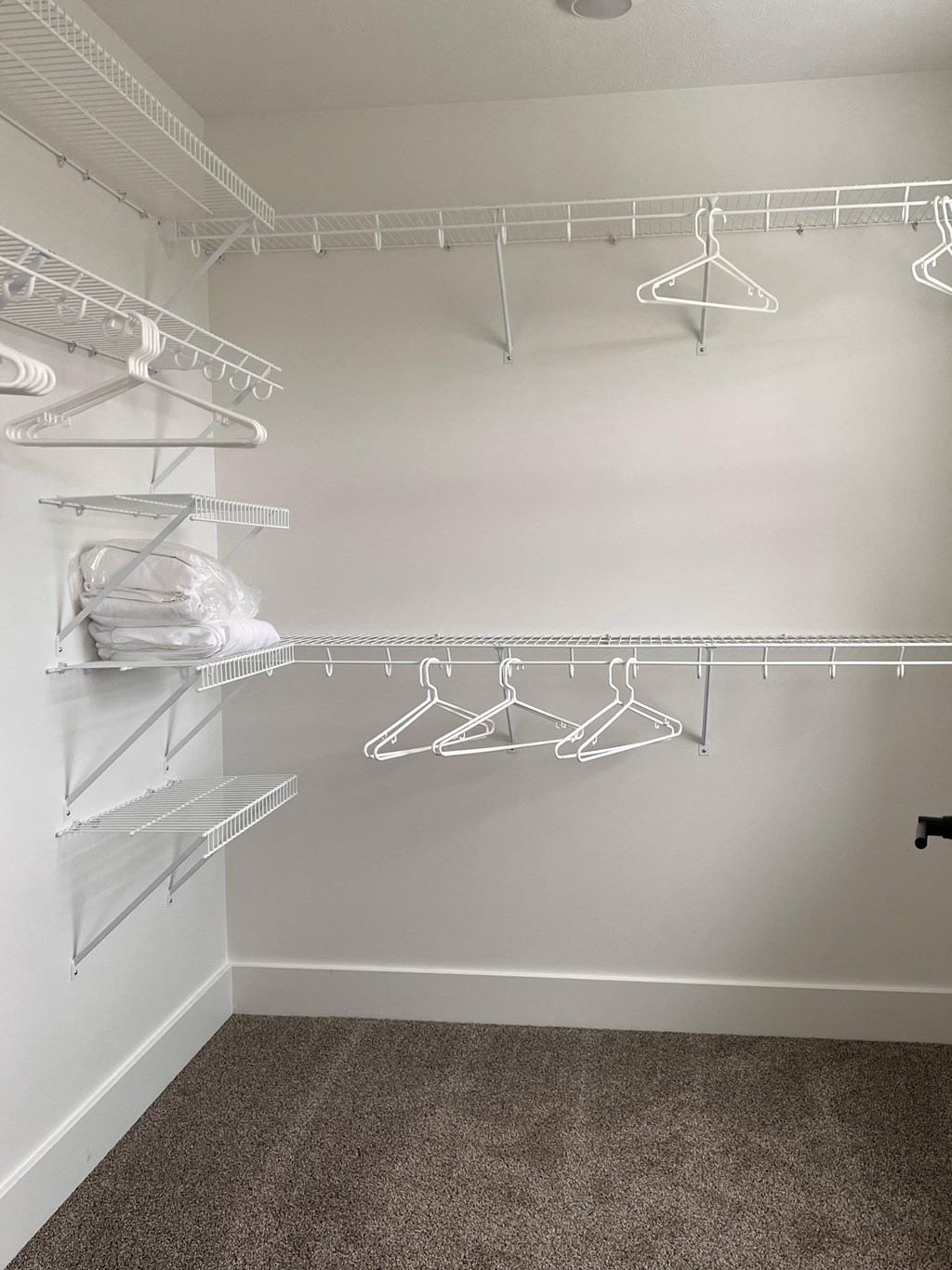 a walk in closet with shelves and hangers on the wall