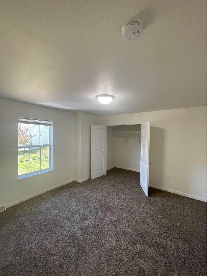 an empty living room with carpet and a window