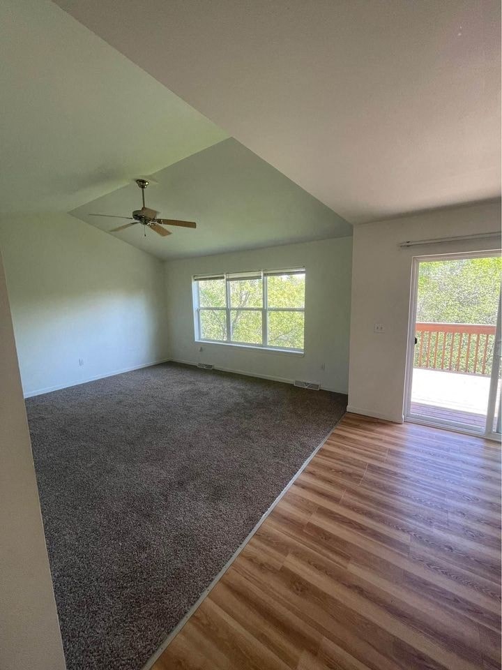 an empty living room with a ceiling fan and a window