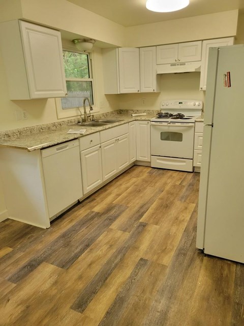 A kitchen with white cabinets and a wooden floor.