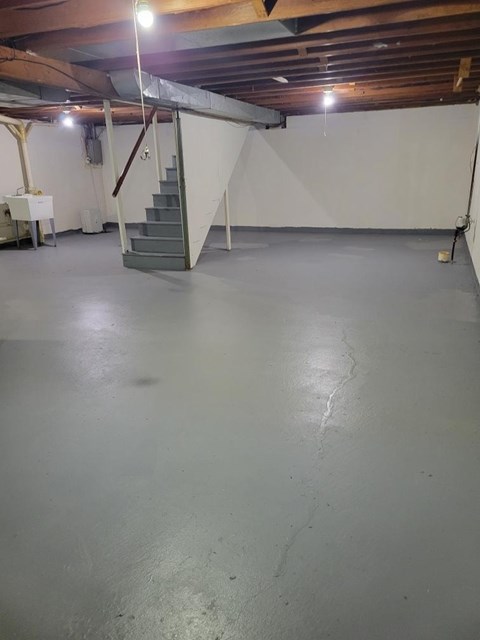 A spacious basement with a concrete floor and a staircase leading to the upper level.