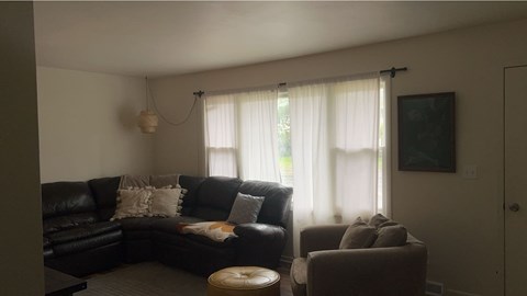 A living room with a black couch and a small ottoman.