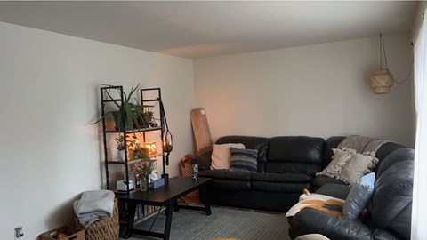 A living room with a black couch and a wooden chair.