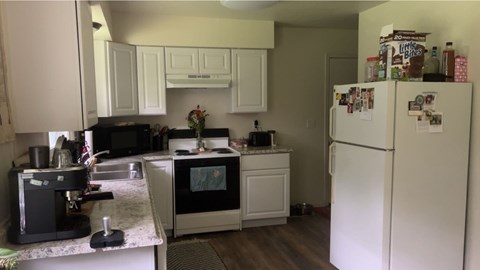 A kitchen with a white fridge and a black coffee maker.