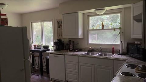 A kitchen with white cabinets and a window overlooking a garden.