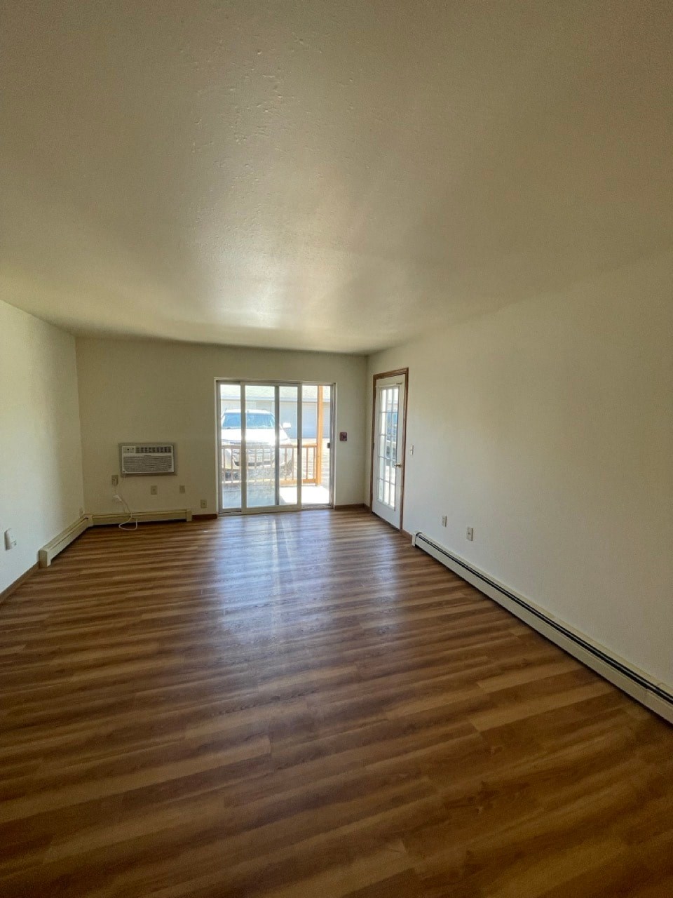 an empty living room with wooden floors and white walls