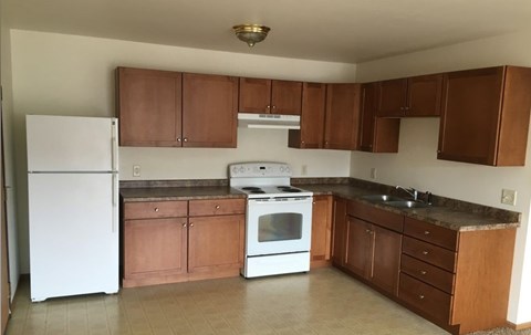 A kitchen with white appliances and brown cabinets.