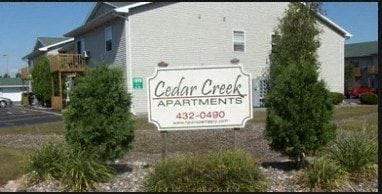 a cedar creek apartments sign in front of a house