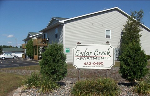 A building with a sign that says Cedar Creek Apartments.