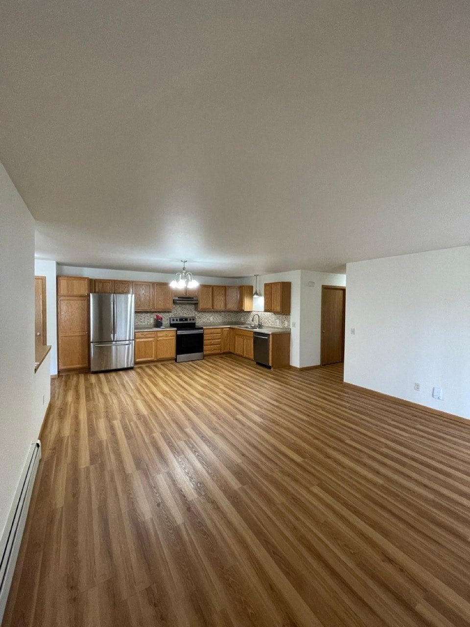 an empty living room and kitchen with wood flooring