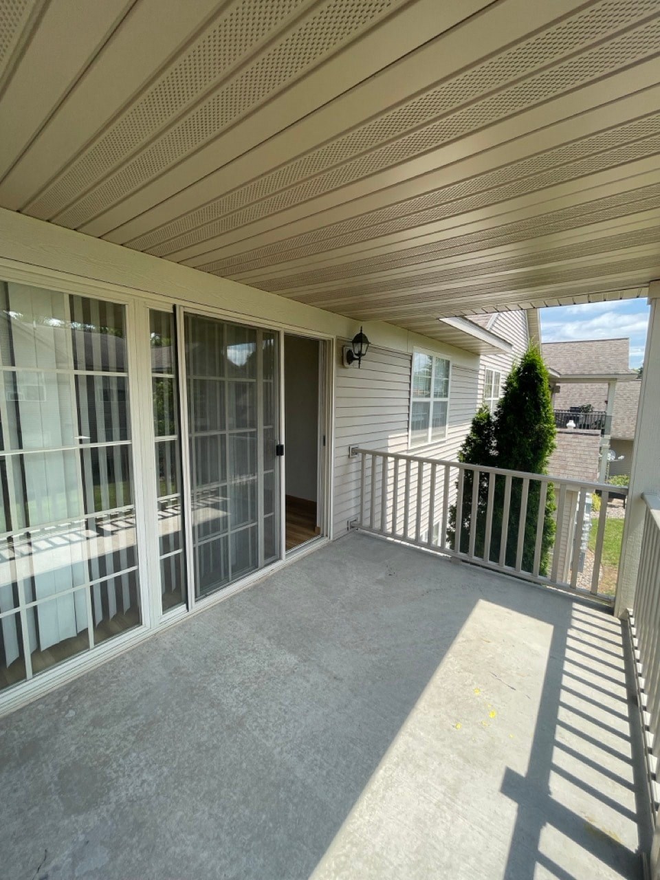 the view from the porch of a white house with glass doors and a patio