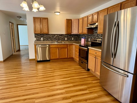 A kitchen with wooden cabinets and a stainless steel refrigerator.
