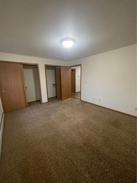 A room with carpeted floor and three doors.