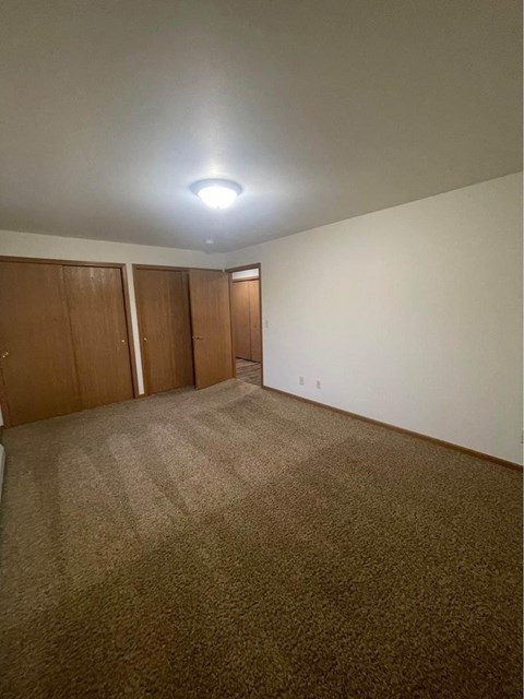 A room with carpeted floor and two doors.