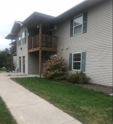 A house with a balcony and a flower bush in front.