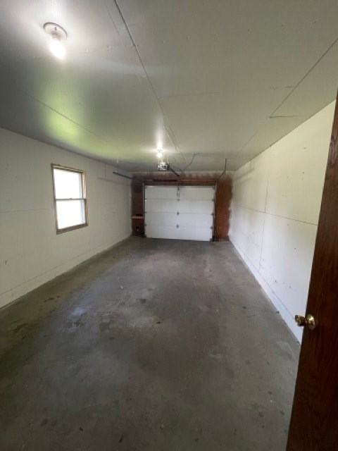 A room with a white ceiling, a window, a door, and a concrete floor.