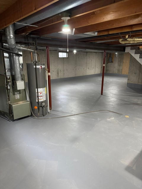 A spacious basement with a concrete floor and a concrete wall.