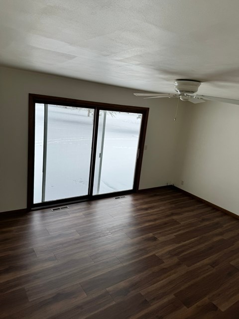 A room with a ceiling fan and sliding glass doors.