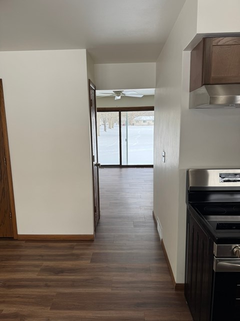 A kitchen with a stove top oven and a wooden floor.