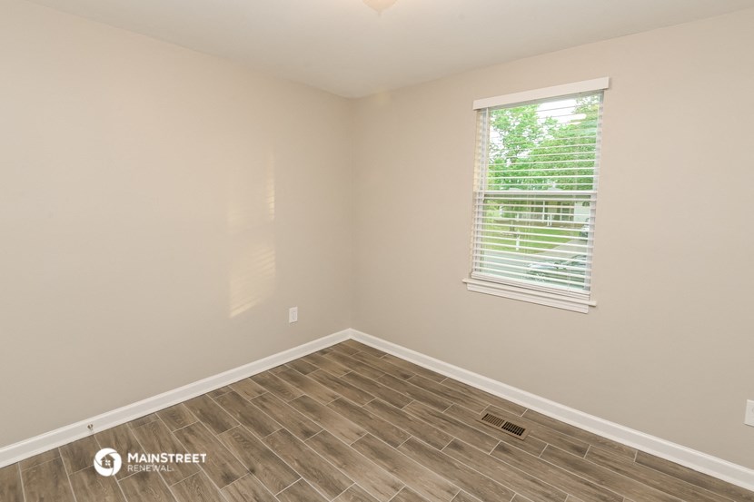 the bedroom of the bridgewater house has a hardwood floor and a window