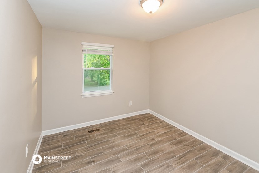 an empty room with wood flooring and a window