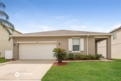 a beige house with a garage door and a lawn