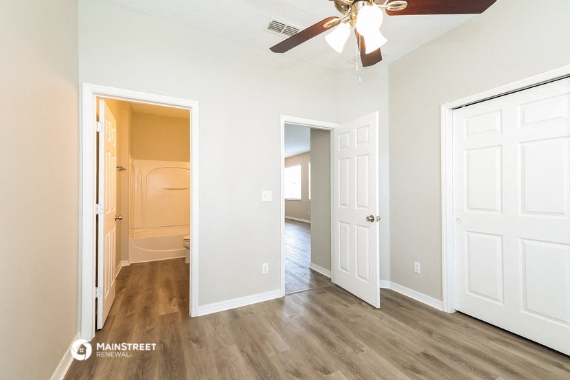 a bedroom with white doors and a ceiling fan