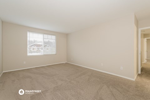 a spacious living room with carpet and a window