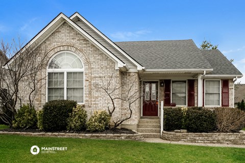 the front of a brick house with a red door