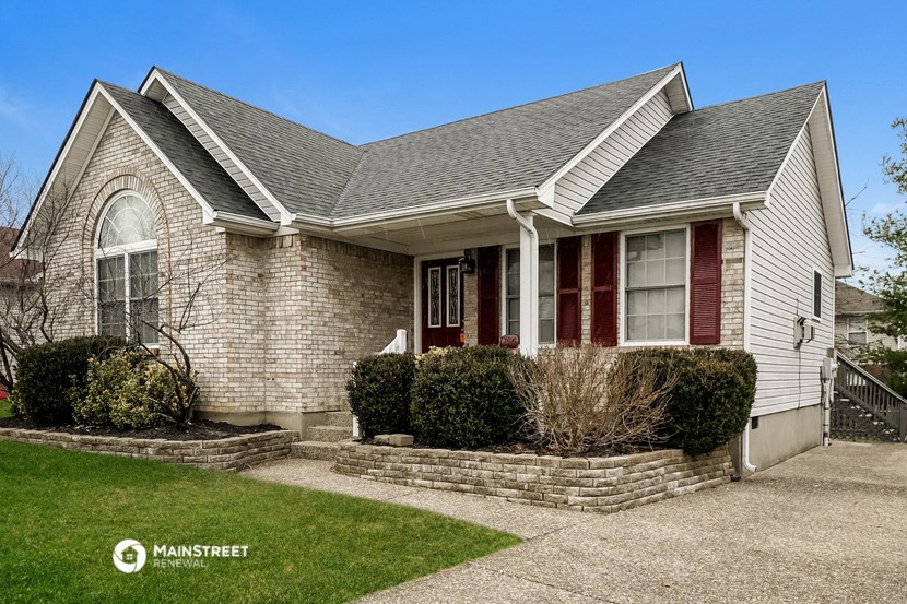 a small brick house with red doors and a lawn
