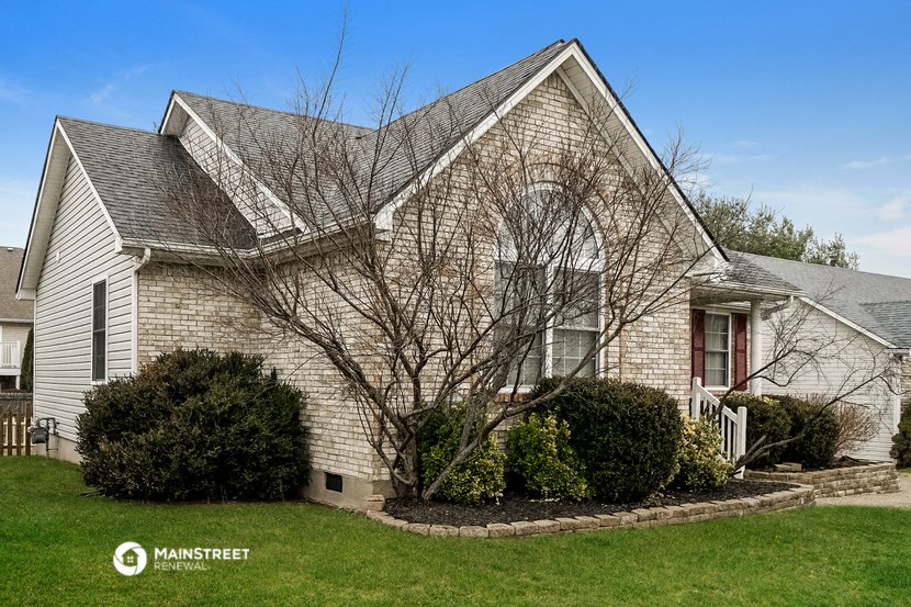 a white brick house with a lawn and shrubs in front of it