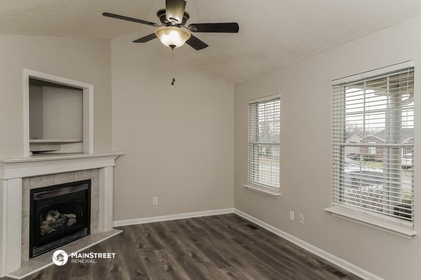 a living room with a fireplace and a ceiling fan