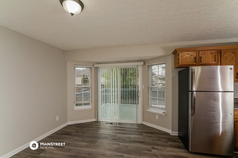 an empty living room with a stainless steel refrigerator