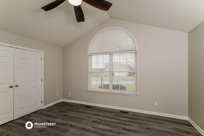 the spacious living room with a large window and a ceiling fan