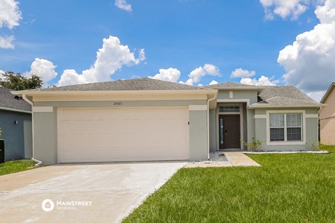 a beige house with a garage door and a lawn