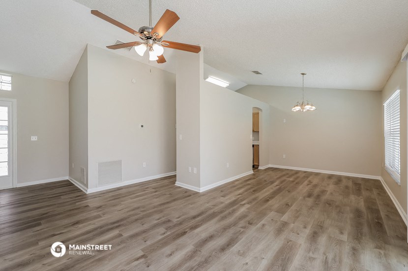 the spacious living room with wood flooring and a ceiling fan