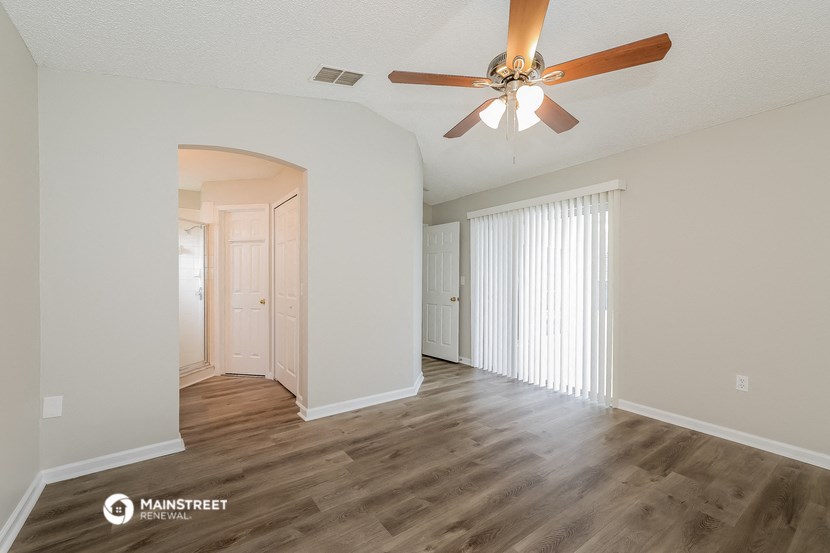 a living room with a ceiling fan and a door to a closet