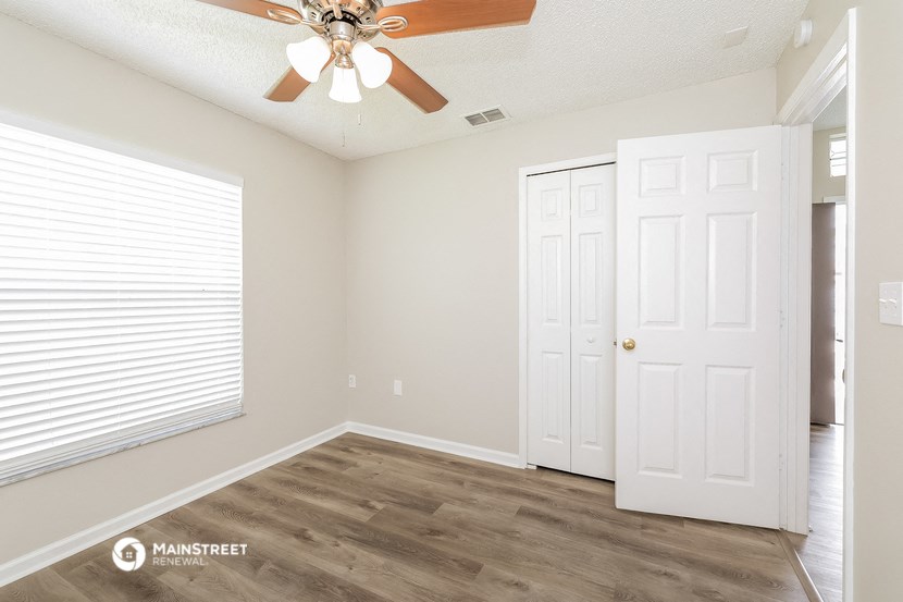 an empty room with a ceiling fan and a window
