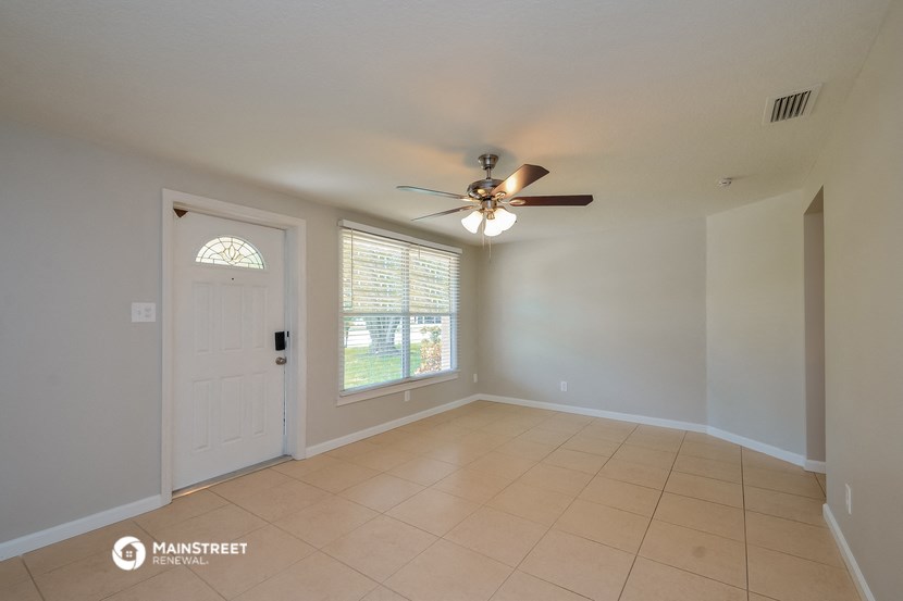 the living room of an empty house with a ceiling fan