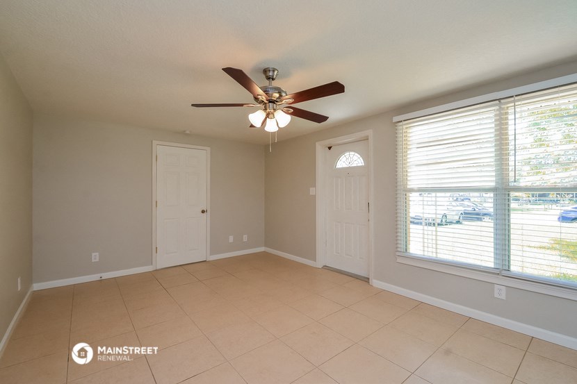 an empty living room with a ceiling fan and a large window