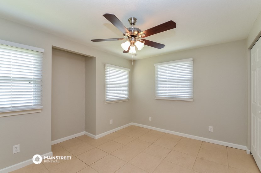 the living room has a ceiling fan and a tiled floor