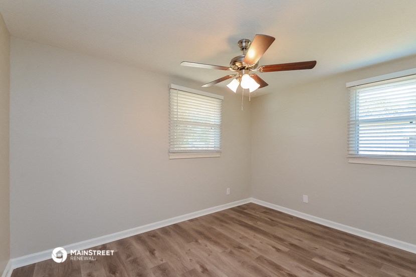 the spacious living room with ceiling fan and wood flooring