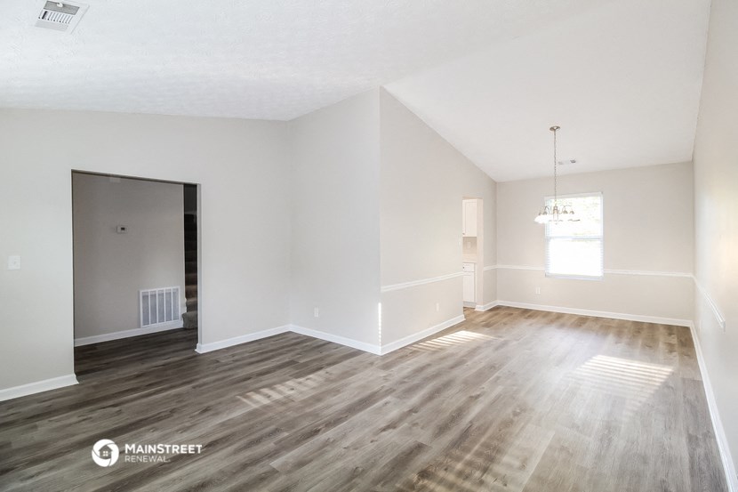 an empty living room with wood floors and white walls