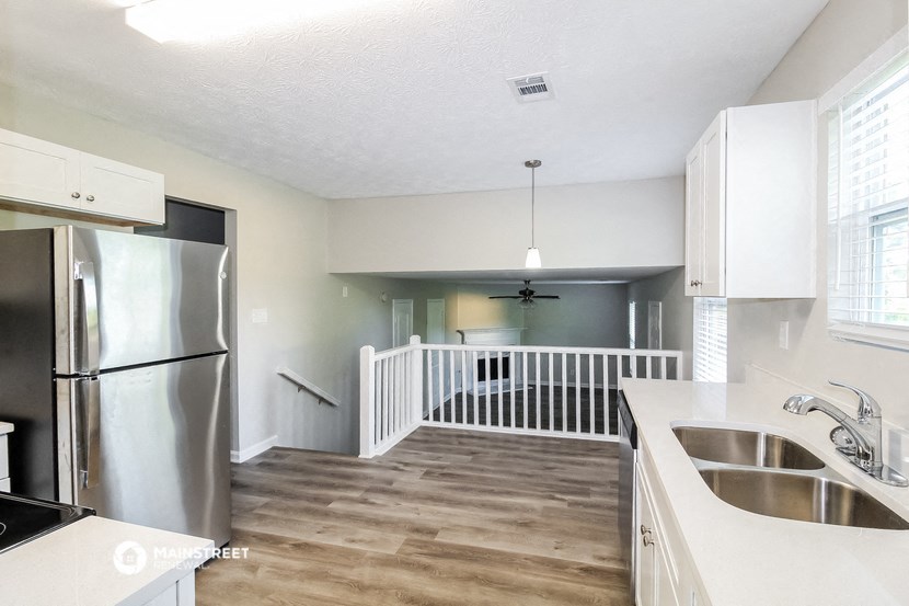 a white kitchen with a stainless steel refrigerator and a sink