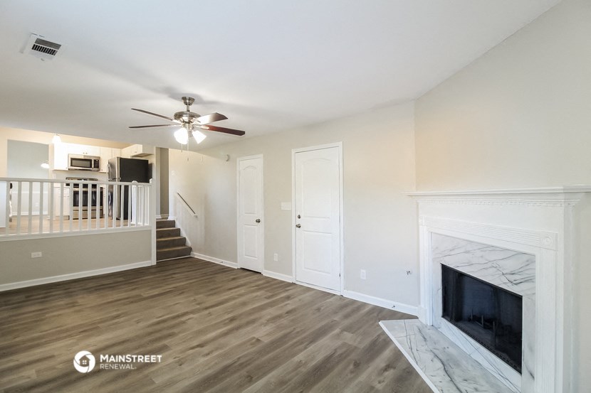 a living room with a fireplace and a ceiling fan